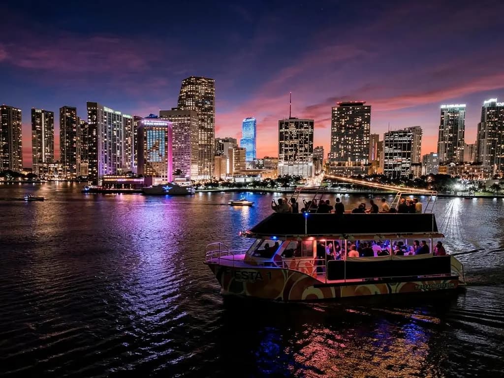 Fiesta tour boat in front of the lit-up Miami skyline at night